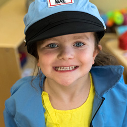 Young girl in mailman costume playing in classroom