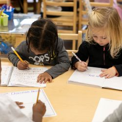 Children writing together during small group learning activity