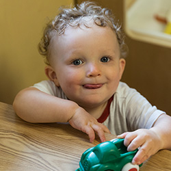 Two year old boy playing with a toy car at daycare